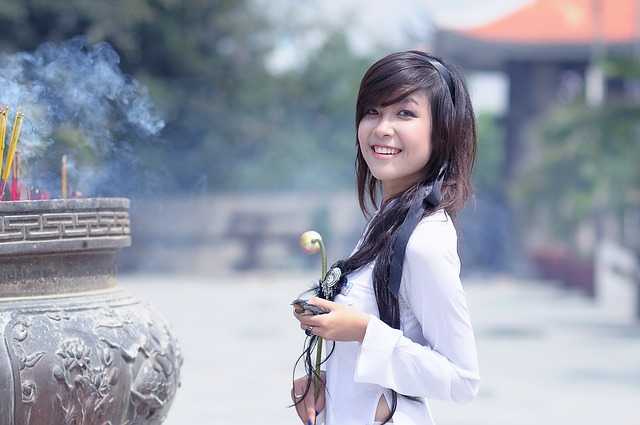 asijská dívka s květinou u kadidel.jpg